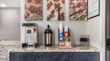 A kitchenette with a coffee machine, a water dispenser, and a coffee cup holder.