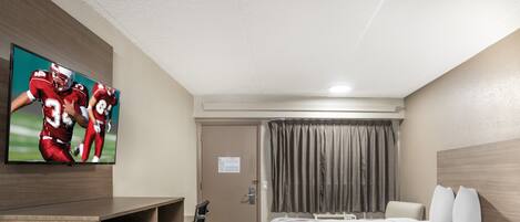 Une chambre d’hôtel comprenant un lit, un bureau avec une télévision, une chaise, une armoire et une porte.