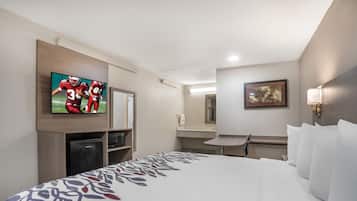 A hotel room with a bed, a television, a desk, and a bathroom.
