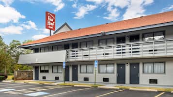 A hotel with a red roof, multiple rooms, and a parking lot with handicapped parking spaces.