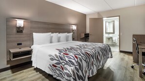 A hotel room with a large bed, bedside tables, a mirror, and a wardrobe. - Red Roof Inn Greenville (Greenville)