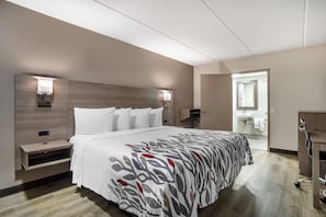 Una habitación de hotel con una cama grande, mesitas de noche, un espejo y un armario.