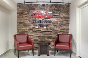 Un área de recepción con pared de piedra y dos sillones de cuero rojo.