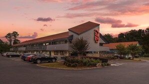 A hotel with a parking lot, a sign for 'Red Roof Inn', and a sunset sky. - Red Roof Inn Greenville (Greenville)