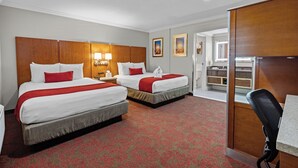 A hotel room with two beds, a desk, and a bathroom visible through an open door.