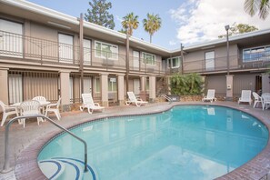 A swimming pool with lounge chairs and a building with balconies and windows.