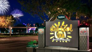 A sign for Del Sol Inn & Resort with a street view in the background.