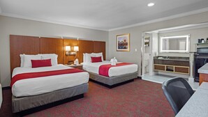 A hotel room with two beds, a desk, a chair, a bathroom with a mirror, and a small kitchenette. - Del Sol Inn - Anaheim Resort (Anaheim)