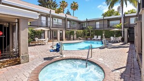 A hotel with a swimming pool, outdoor seating, and a hot tub.
