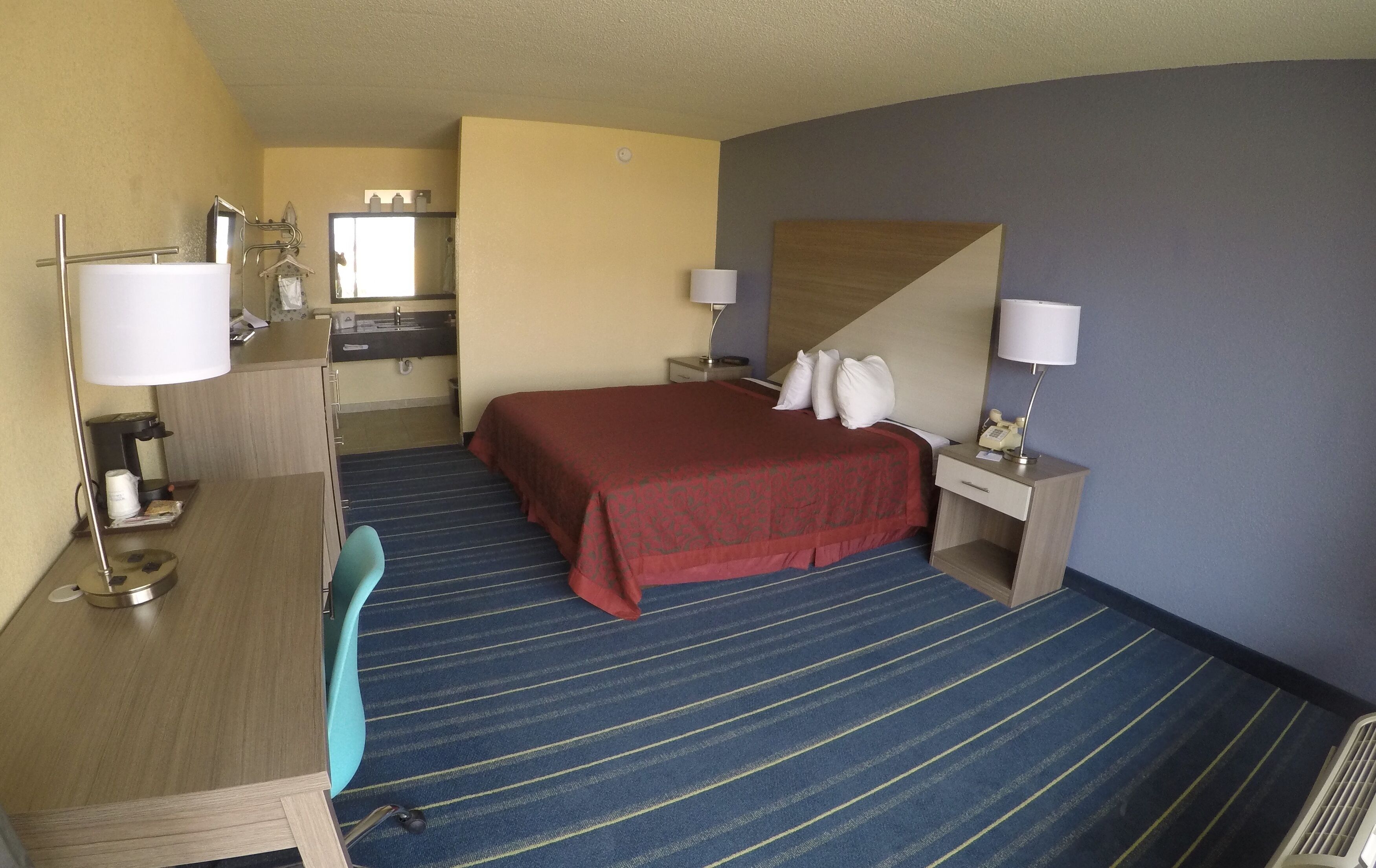 Une chambre d’hôtel comprenant un lit, un bureau, une chaise, une table de chevet et une salle de bain.