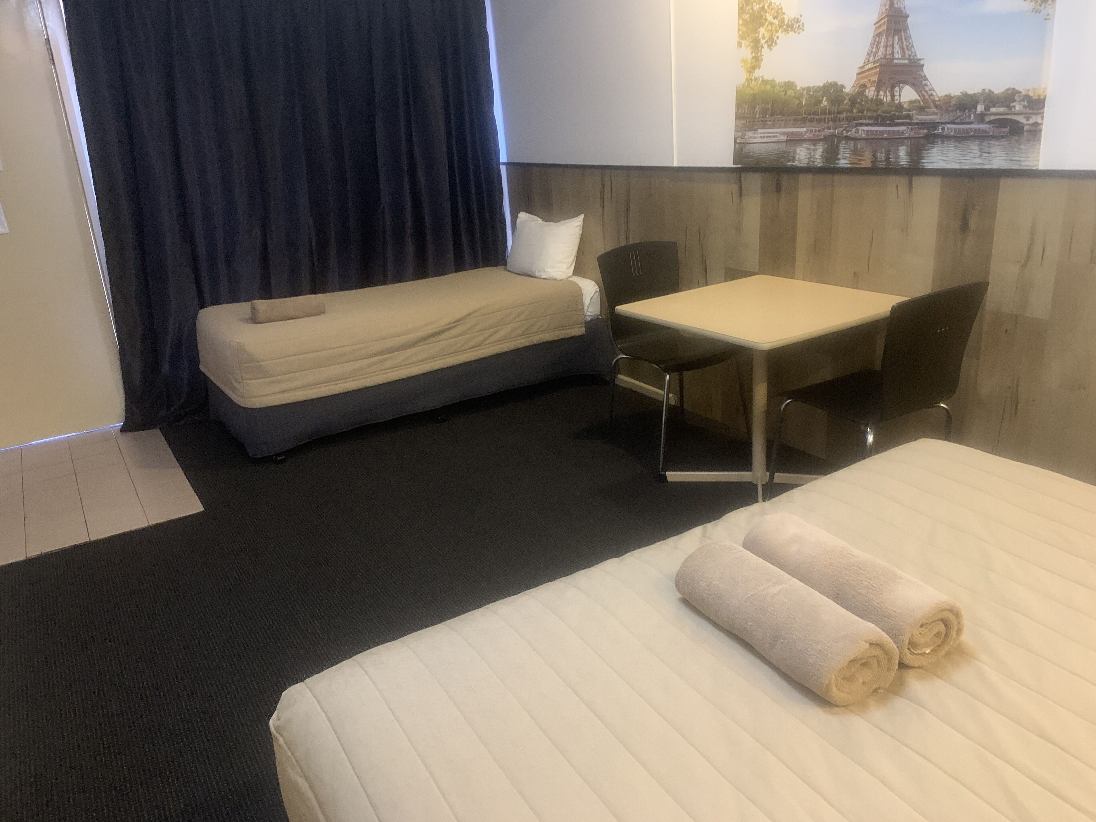 A hotel room with a bed, a desk, a chair, and a view of the Eiffel Tower.