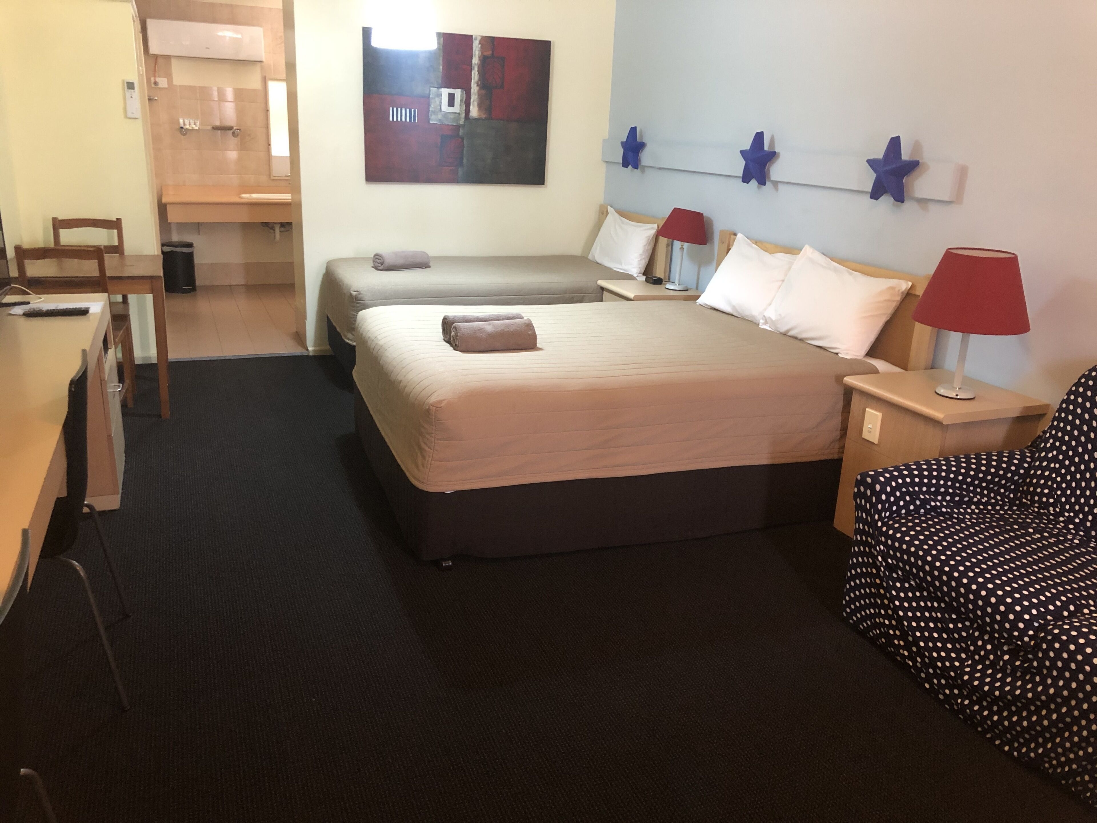 Una habitación de hotel con dos camas, un escritorio, una silla y una mesita.