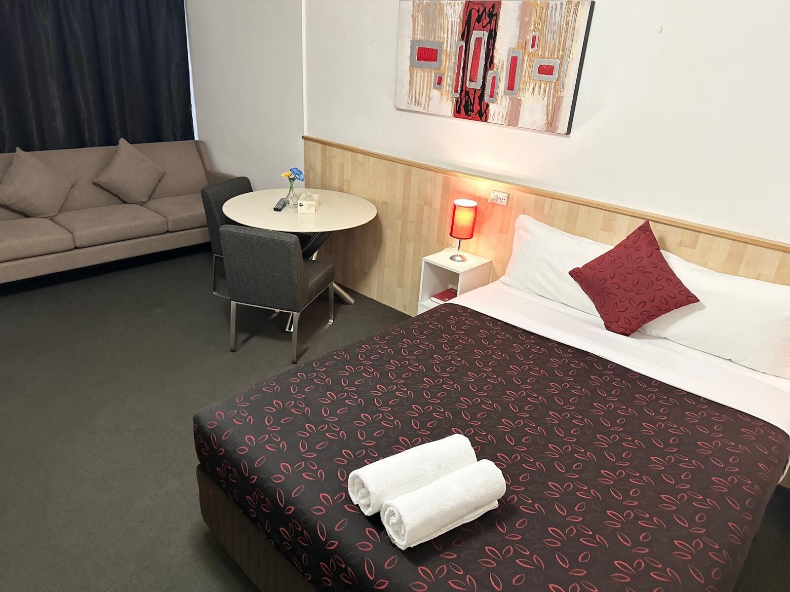 Une chambre d’hôtel avec un lit, un canapé, une petite table et une table de chevet avec une lampe.