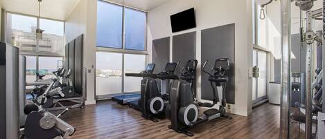 Una palestra con tapis roulant, ellittiche e attrezzature per pesi.