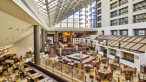 A spacious hotel lobby with multiple dining areas, a central seating area, and a high ceiling with a geometric glass structure. - Hyatt Regency Lexington (Lexington)