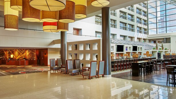 A spacious lobby with high ceilings, modern chandeliers, and a central seating area.
