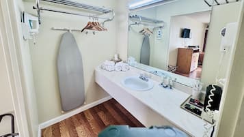 A bathroom with a white sink, a mirror, and a towel rack.