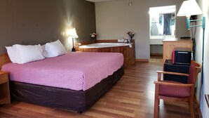 A bedroom with a large bed, a wooden desk, a chair, a window, and a bathroom with a bathtub. - Mountain Home Inn (Mountain Home)