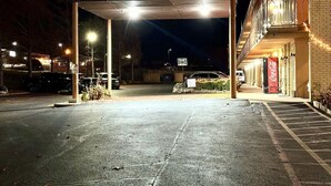 A parking lot with a covered entrance, a Coca-Cola sign, and a building with a balcony. - Mountain Home Inn (Mountain Home)