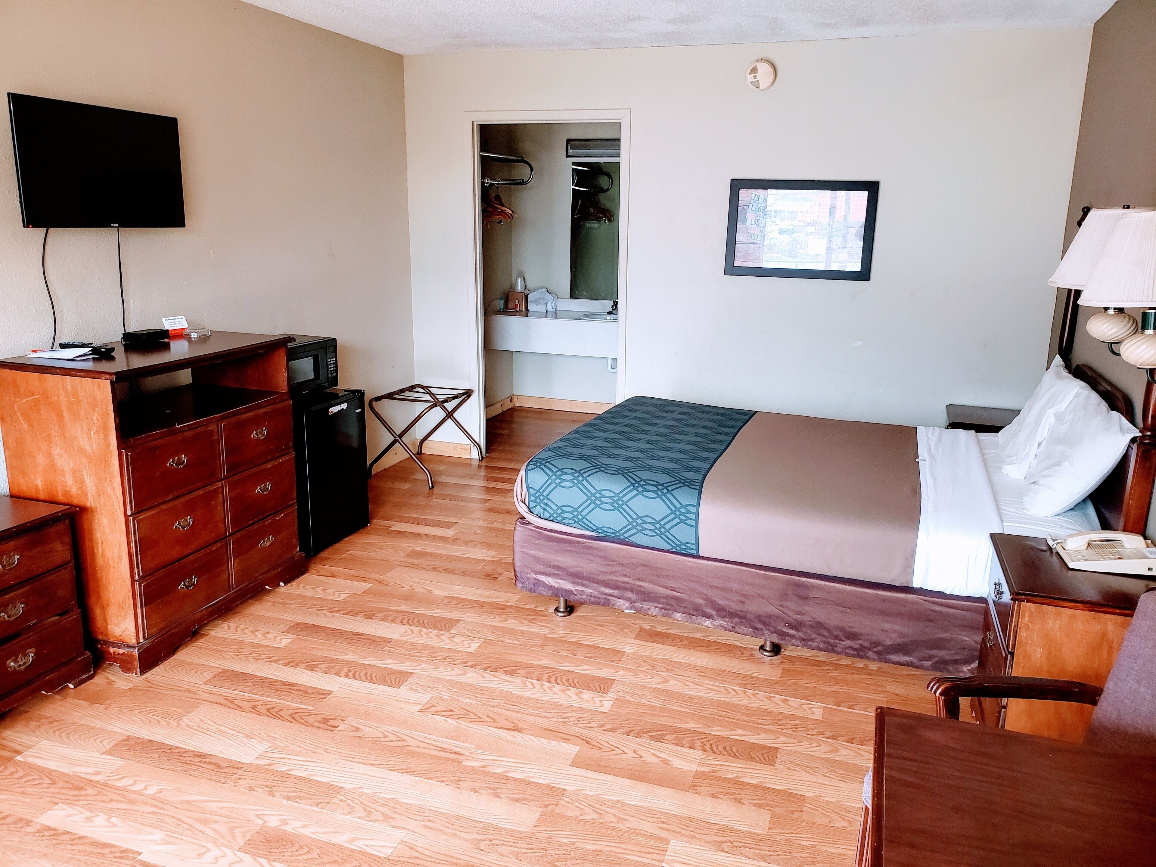 A hotel room with a bed, a desk with a computer, a TV, and a mirror.