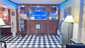 A hotel lobby with a check-in counter, a bulletin board with flyers, a clock, and a vending machine. - Mountain Home Inn (Mountain Home)