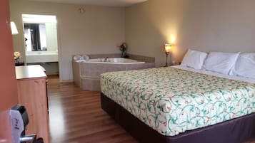A hotel room with a large bed, a separate bathroom with a bathtub, and a desk with a chair.