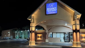 A Regency Inn & Suites building at night with illuminated signage, a covered entrance, and a parking area. - Regency inn and Suites (Pensacola)