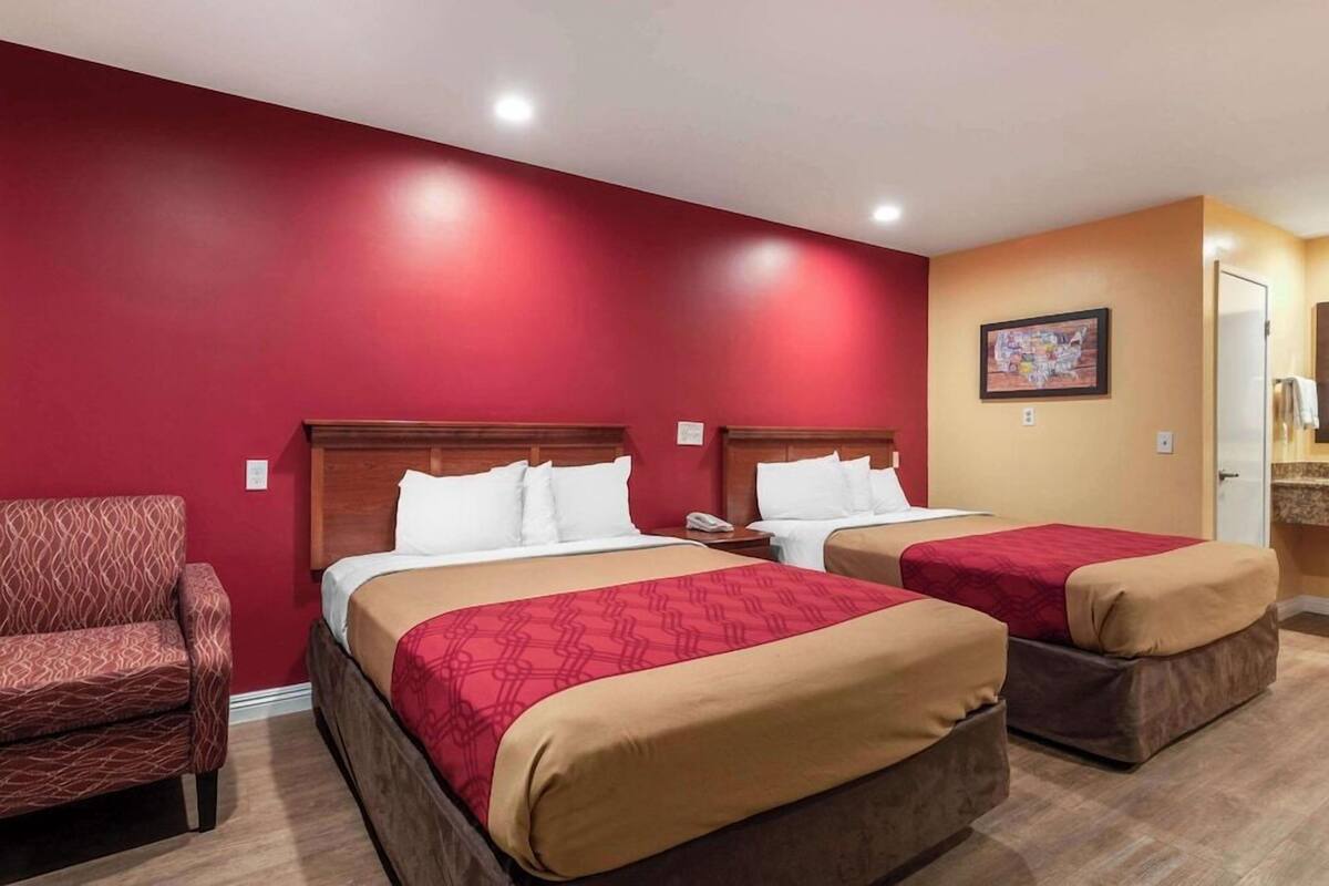A hotel room with two beds, a sofa, and a painting on the wall.