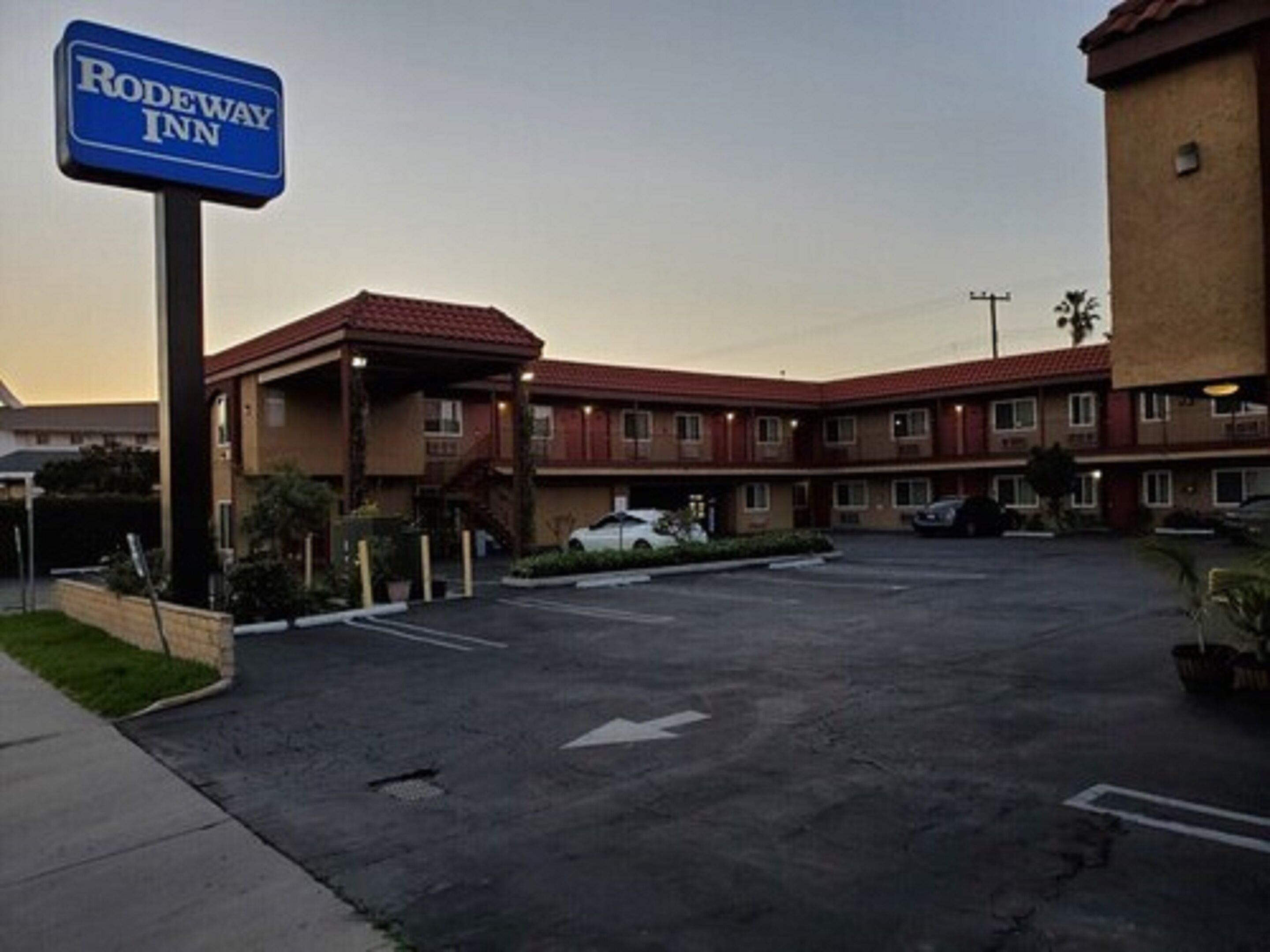 A Rodeway Inn with a parking lot and a building with a red-tiled roof.