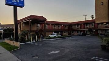 A Rodeway Inn with a parking lot and a building with a red-tiled roof.