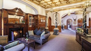 A grand room with a fireplace, a sofa set, a coffee table, and a decorative ceiling. - Macdonald Kilhey Court (Wigan)
