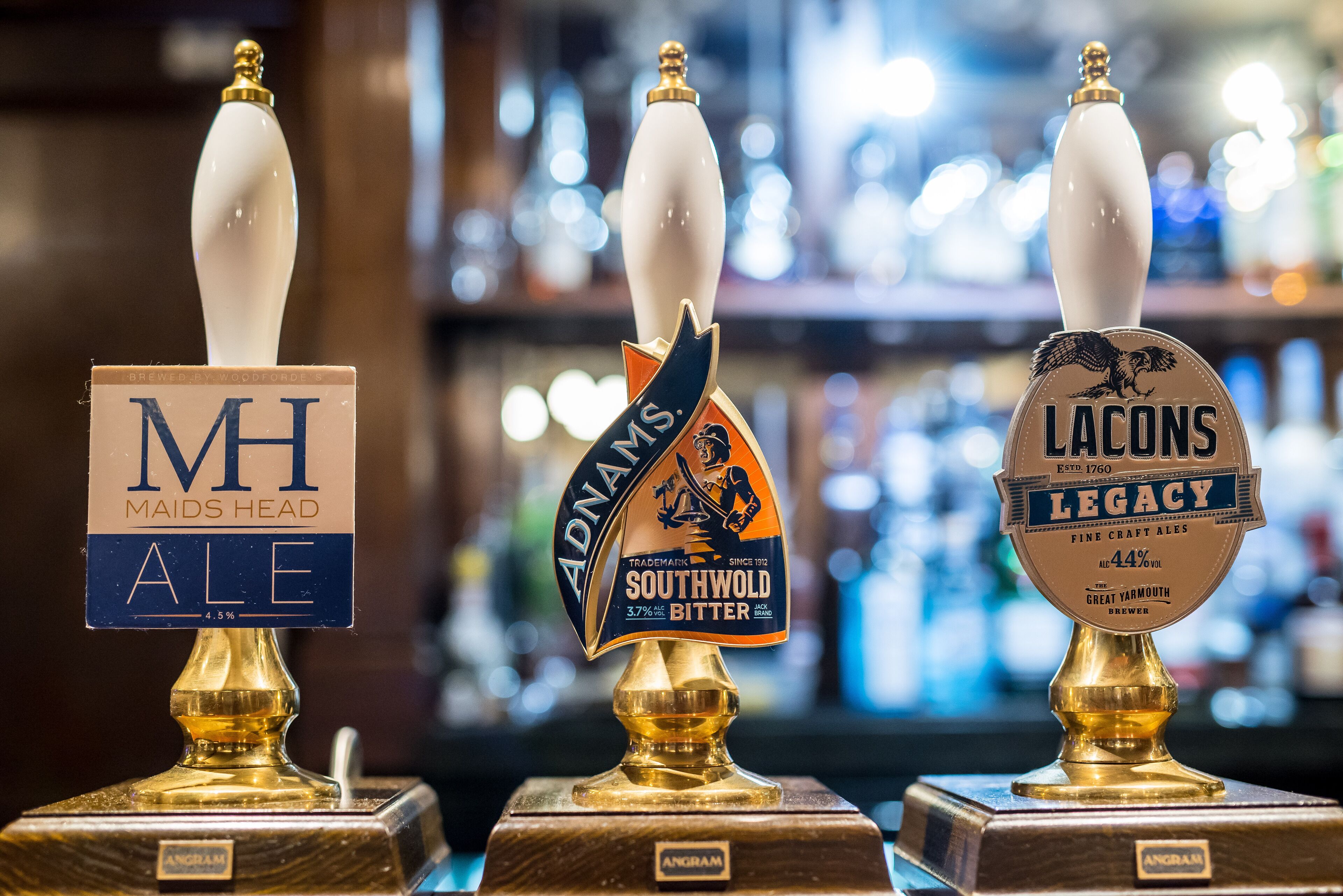 Três torneiras de cerveja com rótulos: 'Maids Head Ale', 'Adnays Southwold Bitter' e 'Lacons Legacy'.
