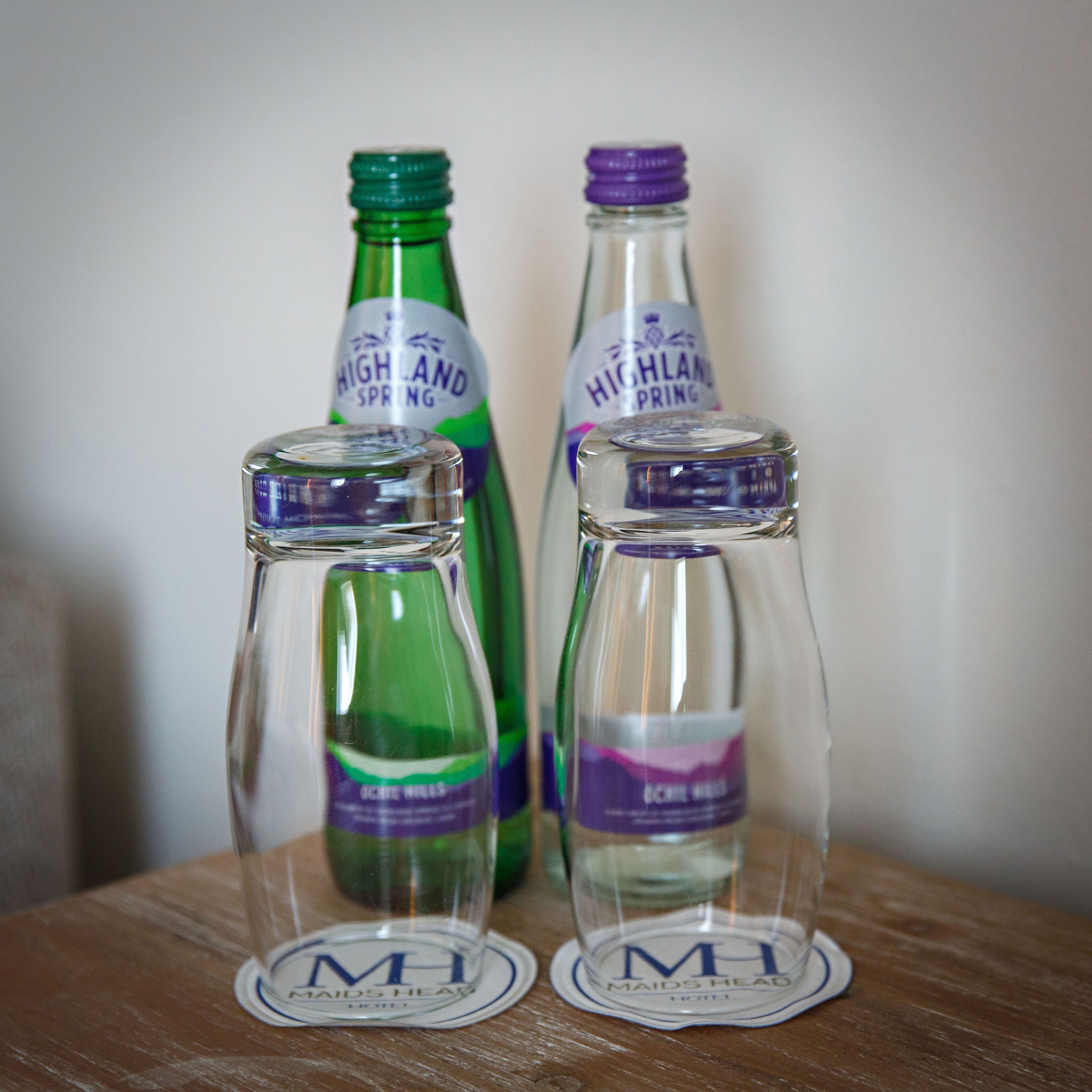 Three glass bottles with labels on a wooden surface.