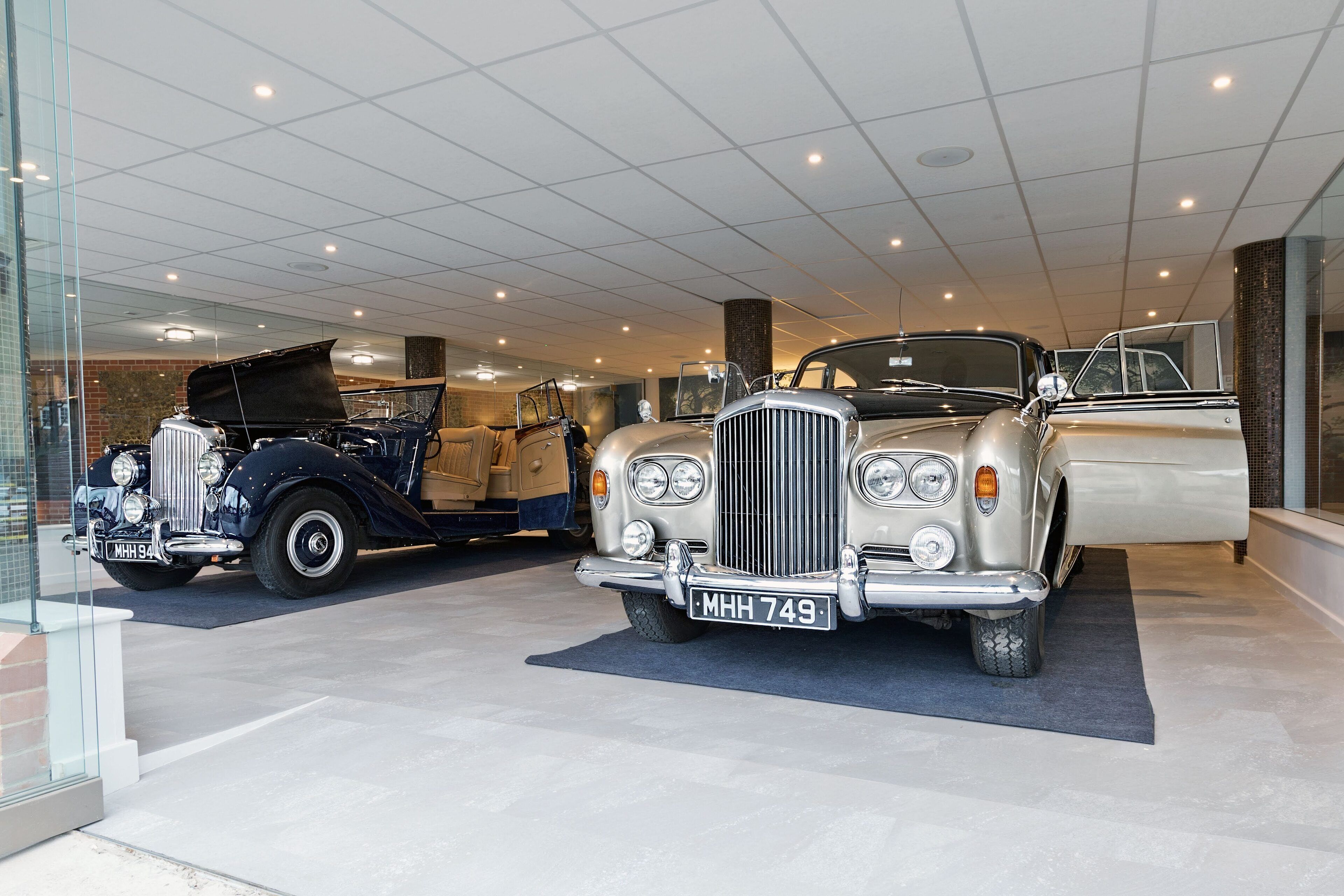 Een showroom met klassieke auto's, waaronder een Rolls-Royce en een Bentley, tentoongesteld binnen.