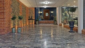A lobby with a brick wall, tiled floor, and a wooden door.