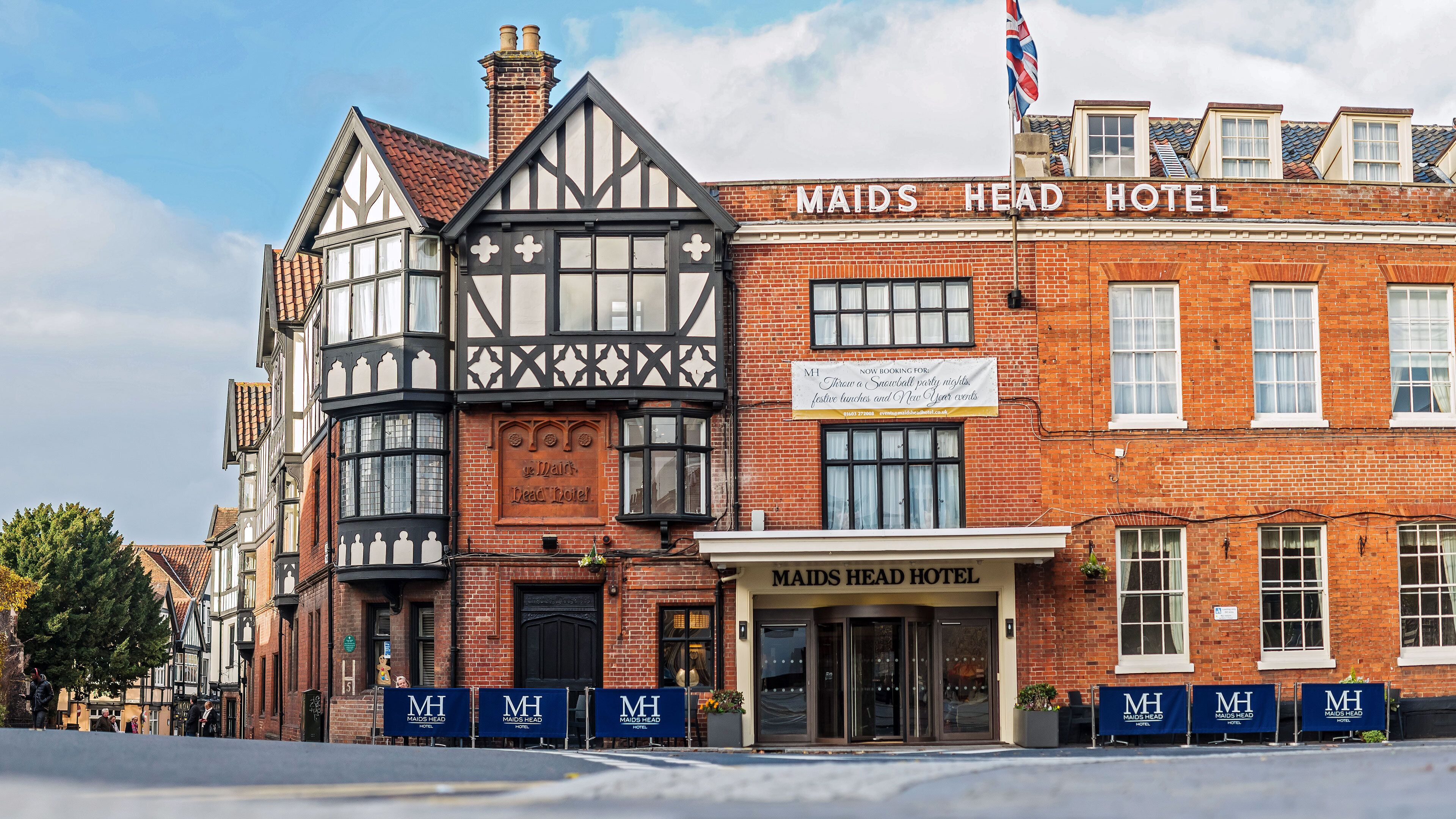 Un edificio tradicional de entramado de madera con un letrero que indica el Hotel Maids Head.