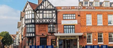 Een traditioneel vakwerkhuis met een bordje voor Maids Head Hotel.