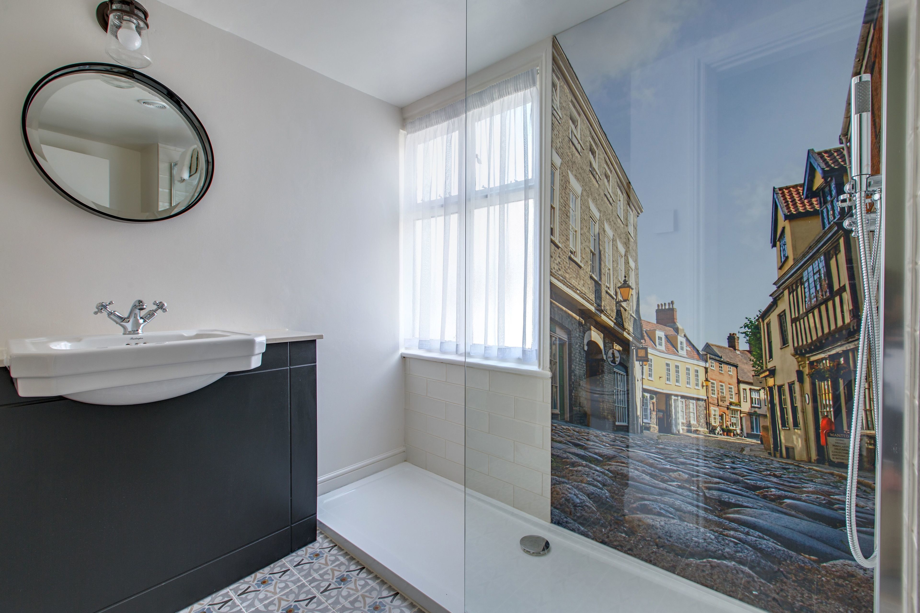 A bathroom with a white sink, dark cabinet, and a large window.