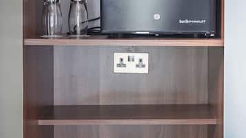 Un mueble de madera con una computadora portátil, dos botellas de vidrio, una tetera y una cafetera.