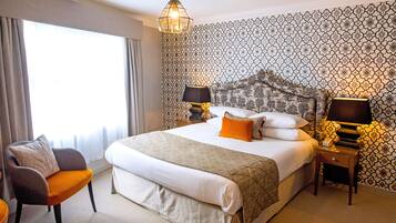 Ein Hotelzimmer mit einem großen Bett, zwei Nachttischlampen, einem Sessel und einer Wand mit Muster.