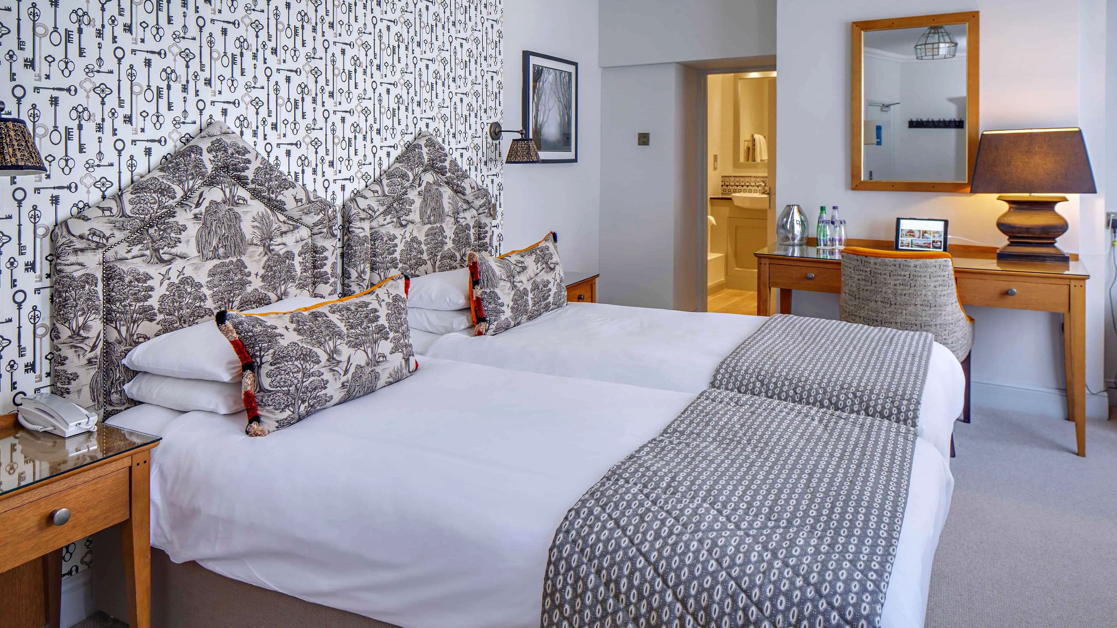 Une chambre d’hôtel avec un grand lit, un bureau, une chaise et un miroir.