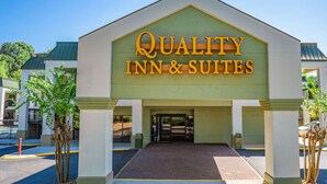 De gevel van een hotel genaamd 'Quality Inn & Suites', met een duidelijke ingang, een groen dak en een verharde oprit.
