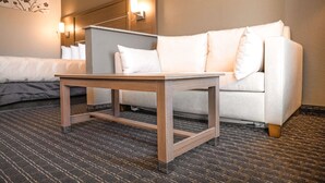 Een hotelkamer met een bed, een witte bank, een houten bijzettafeltje en een wandlamp.