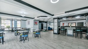 Un espace intérieur spacieux, doté de nombreuses tables et chaises, d’un comptoir central et de grandes fenêtres laissant entrer la lumière naturelle.