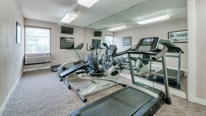 Une salle de sport équipée de tapis de course, de vélos d’appartement et d’un appareil d’aviron.