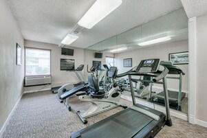 Un gimnasio con cintas de correr, bicicletas estáticas y una máquina de remo.