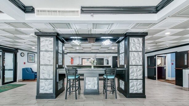 Un intérieur moderne avec un espace bar, deux tabourets de bar et un séparateur à motifs géométriques.