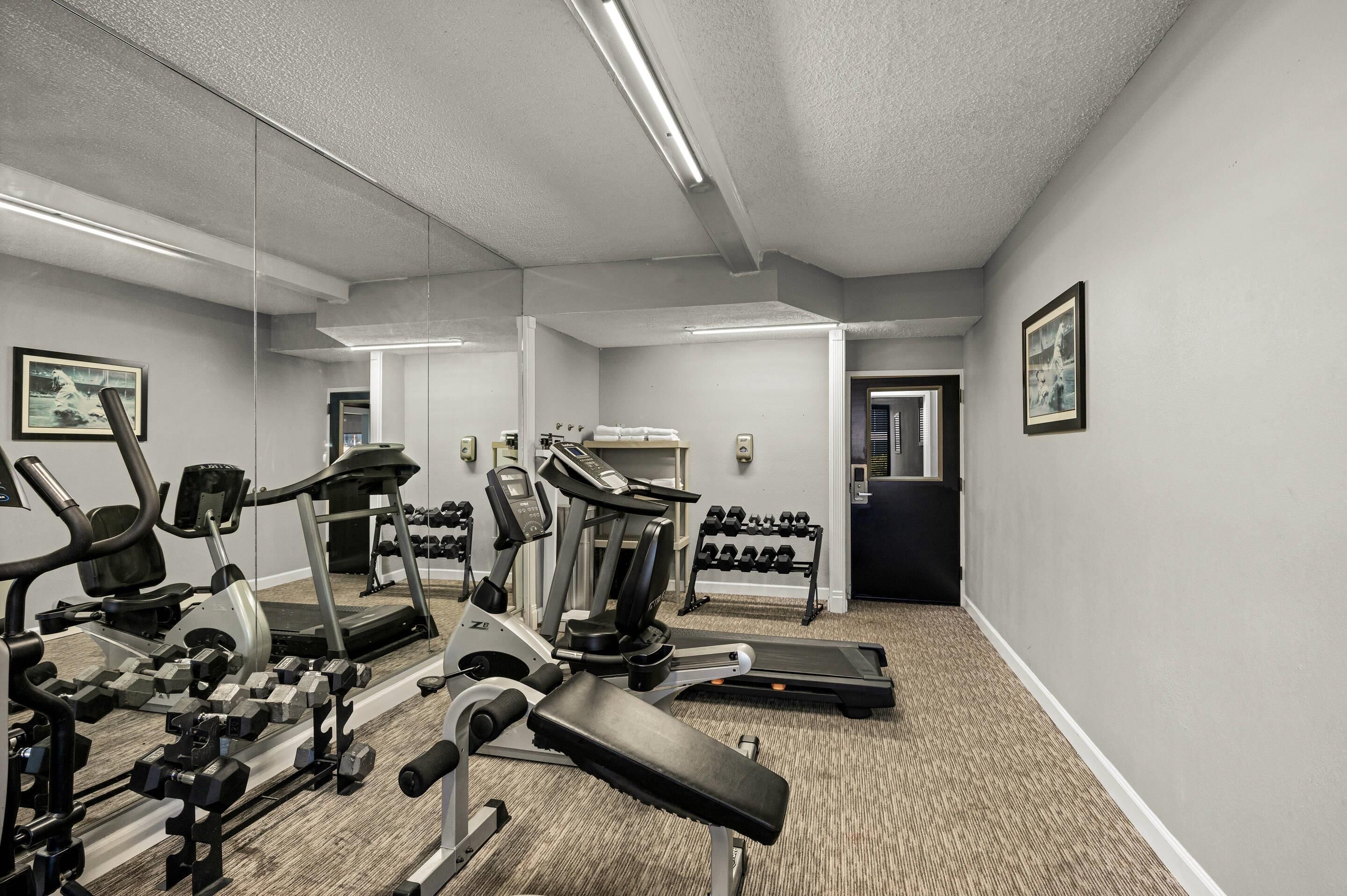 Ein Fitnessstudio mit Cardiogeräten, Gewichten und einem Spiegel.
