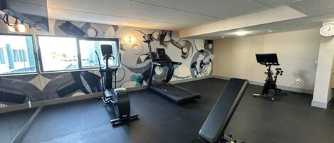 A gym with treadmills, an elliptical, and a bench.