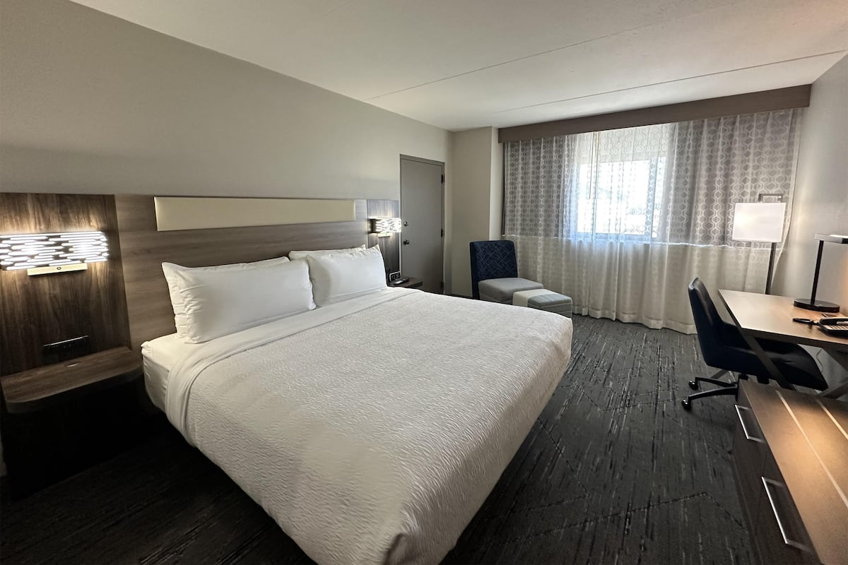 Een hotelkamer met een groot bed, een bureau, een stoel en een raam met gordijnen.